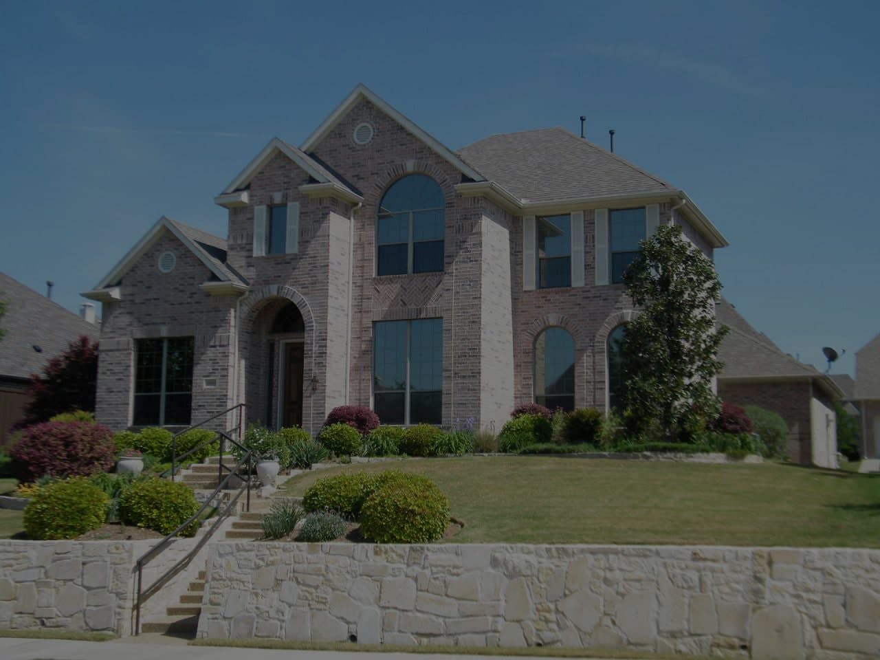 Brick home for sale featuring a stone landscape walkway leading to a vaulted entrance, showcasing elegant curb appeal and quality exterior design, perfect for prospective homebuyers seeking a luxurious and welcoming property